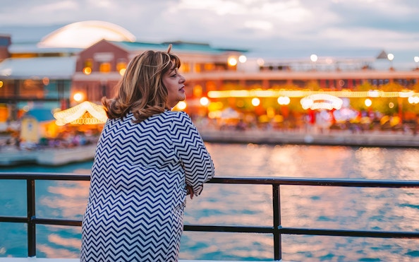 Woman enjoying Chicago skyline from a dinner cruise at sunset.