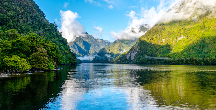 Doubtful Sound fjord with misty mountains and calm water at dawn, New Zealand.