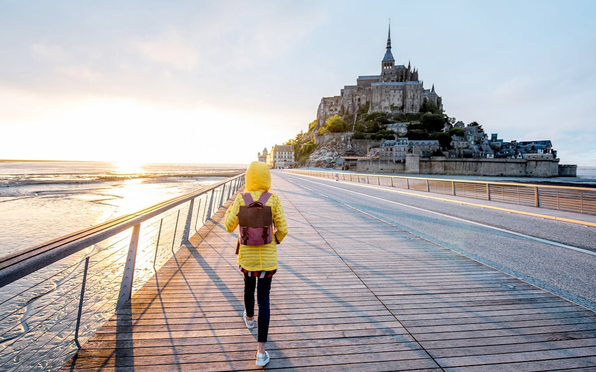 Traveler crossing bridge to Mont Saint Michel, France.