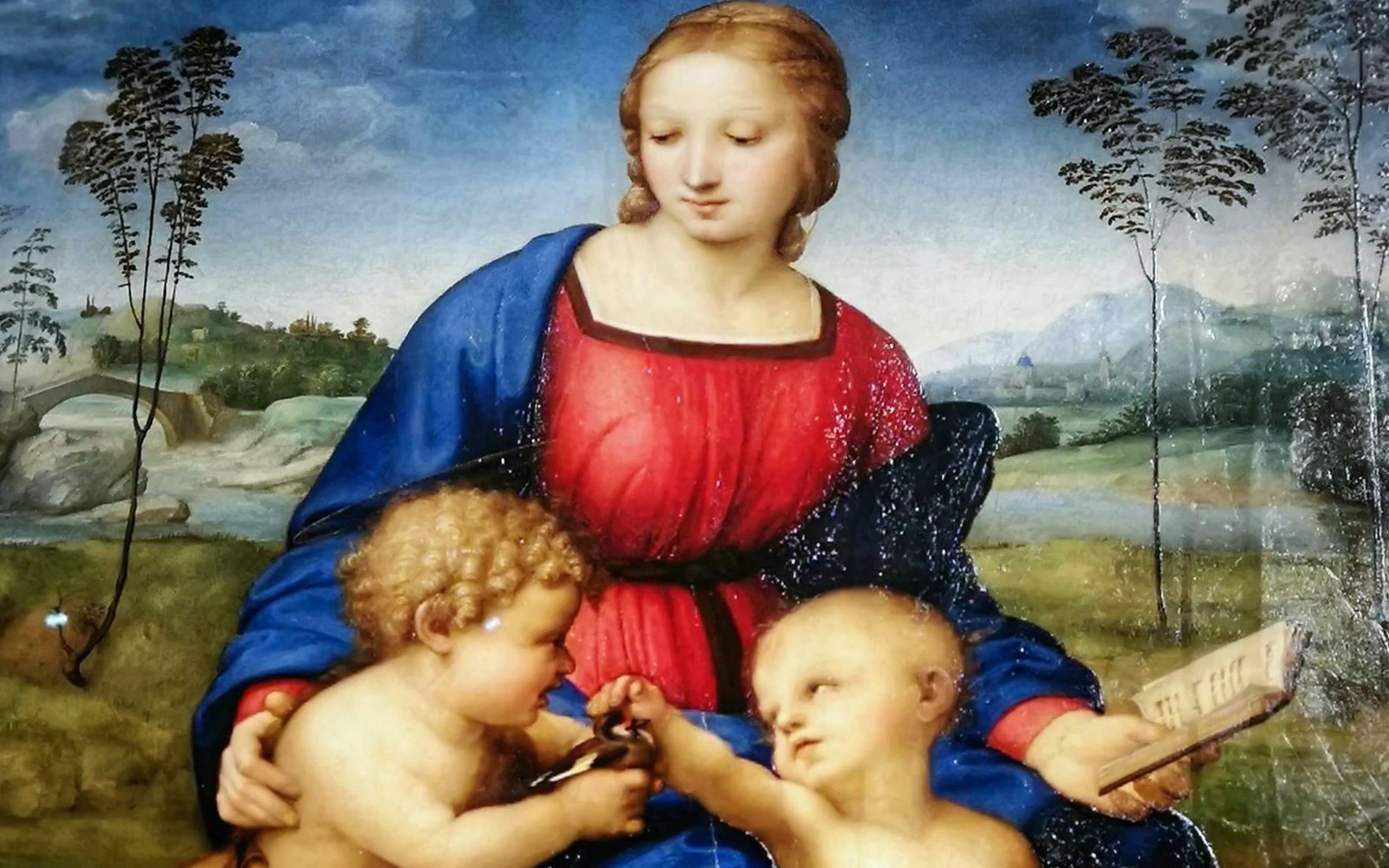 A obra de arte "Madonna del Cardellino", de Rafael, exibida na Galeria Uffizi, mostra Maria em vermelho e azul vibrantes, com o Menino Jesus e o jovem João Batista em um cenário pastoral detalhado