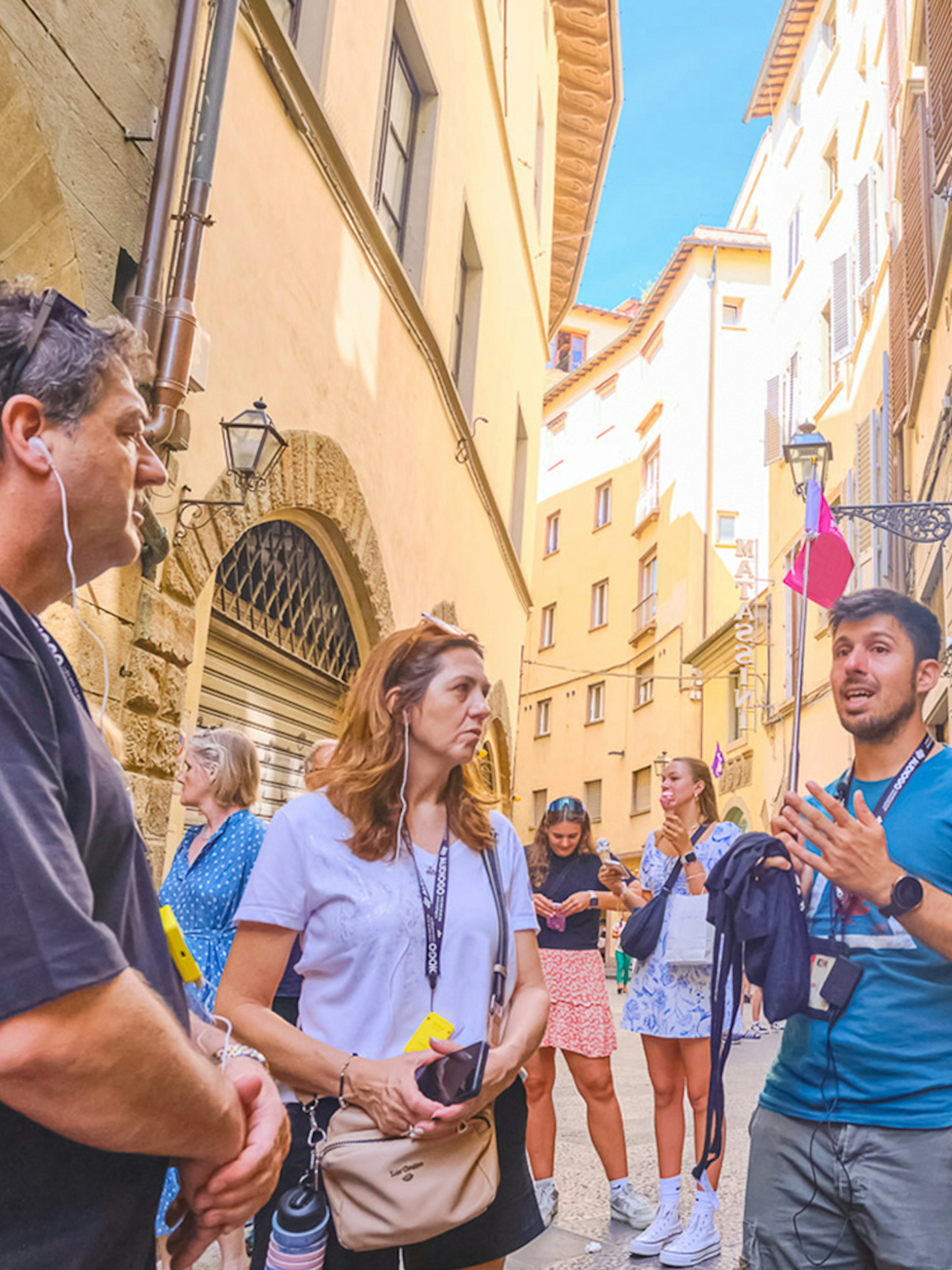 Tour group listening to a guide in a narrow street in Florence.