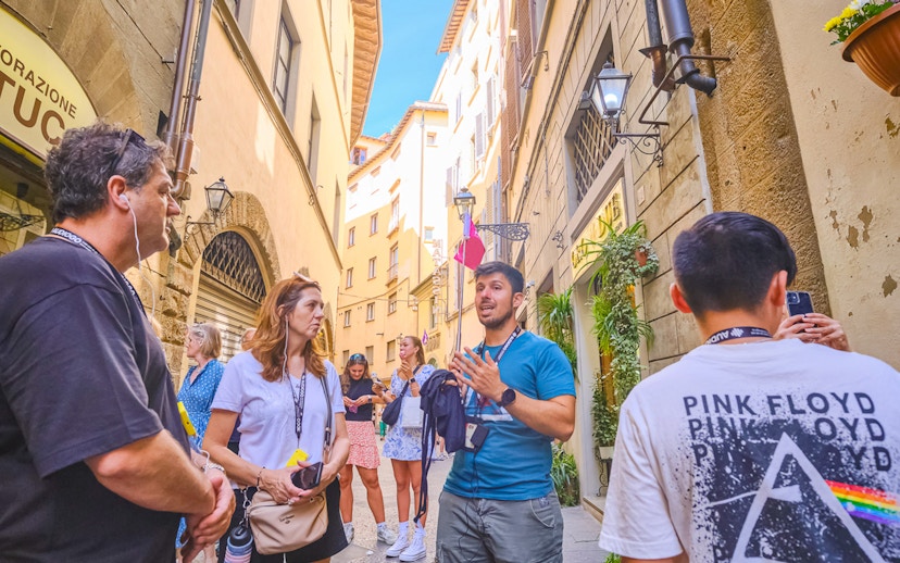 Tour group listening to a guide in a narrow street in Florence.