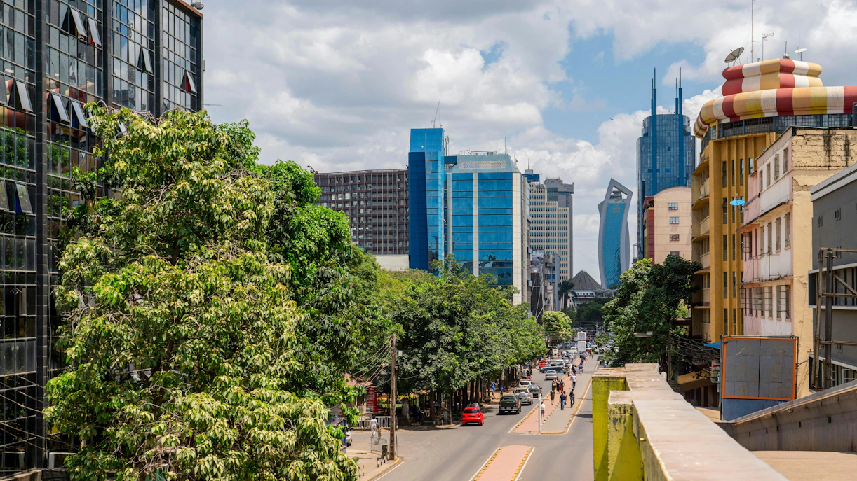 Nairobi street with modern skyscrapers and trees lining the road.