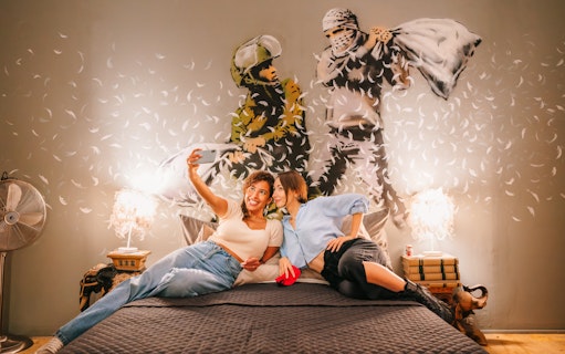 Visitors taking a selfie in front of Banksy artwork at Banksy Museum Barcelona.