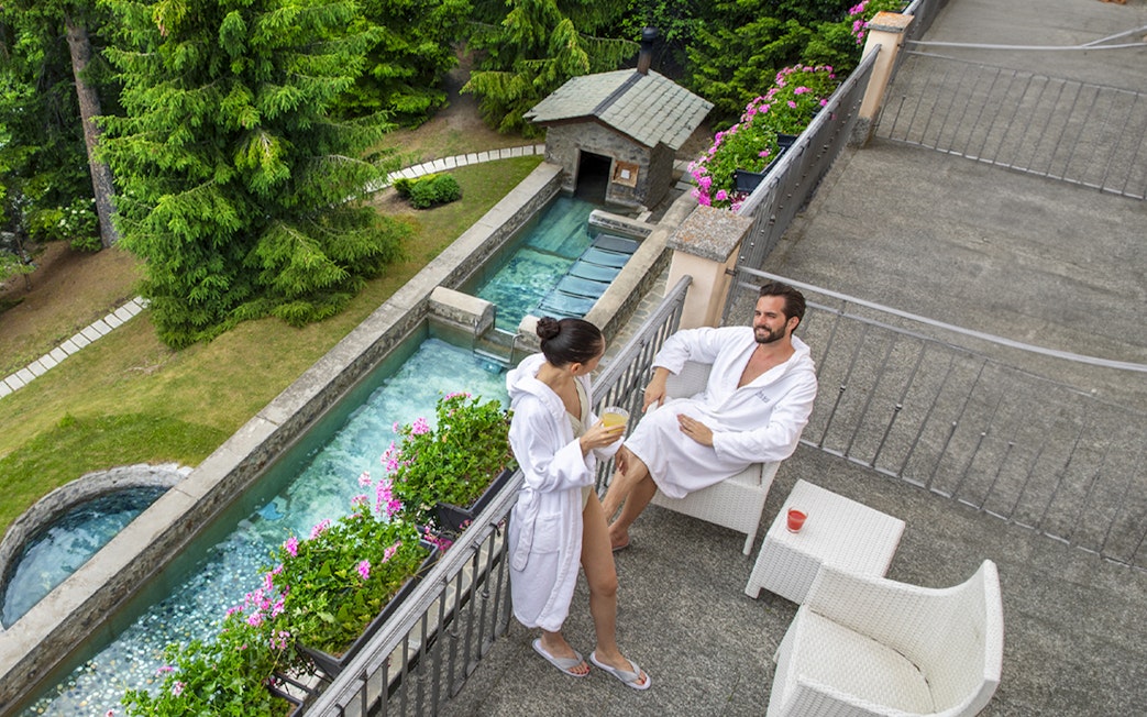 Couple relaxing in robes at QC Terme Bagni Nuovi di Bormio spa terrace.