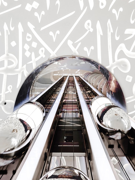 Futuristic elevator inside Museum of the Future, Dubai, with Arabic calligraphy walls.