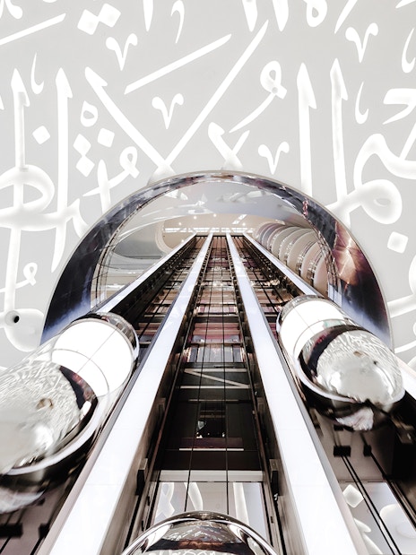 Futuristic elevator inside Museum of the Future, Dubai, with Arabic calligraphy walls.