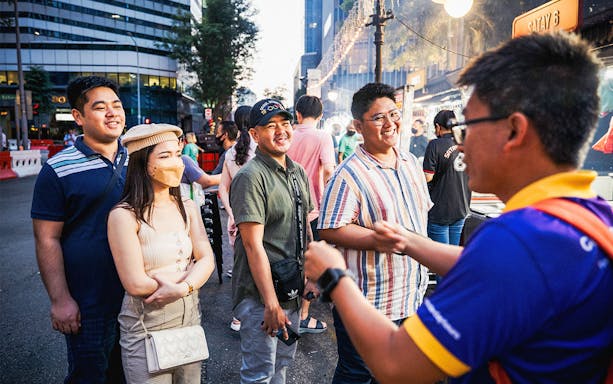 Tour group enjoying Singapore street food night tour with guide.