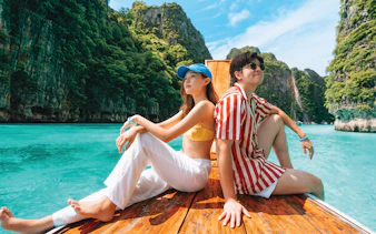 Tourists on a speedboat near Phi Phi Island's limestone cliffs, Phuket.
