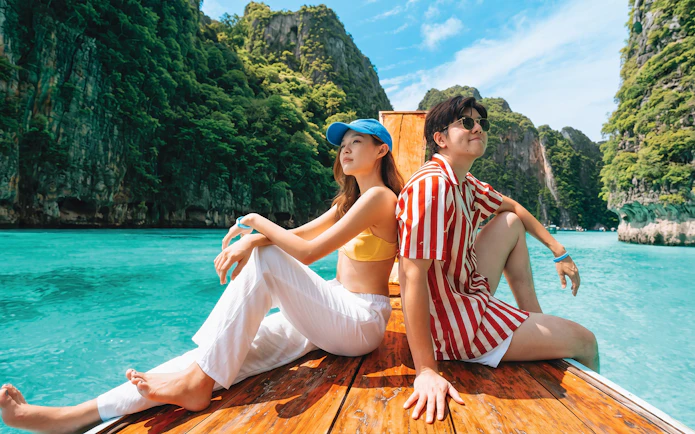 Tourists on a speedboat near Phi Phi Island's limestone cliffs, Phuket.