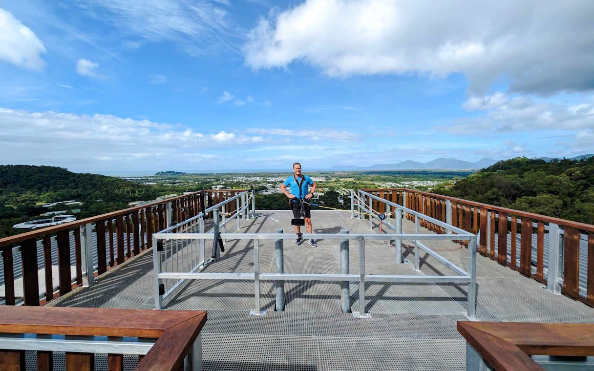 Person standing on a rooftop platform with scenic view, preparing for a roof jump in Cairns, Australia.