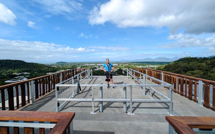Person standing on a rooftop platform with scenic view, preparing for a roof jump in Cairns, Australia.