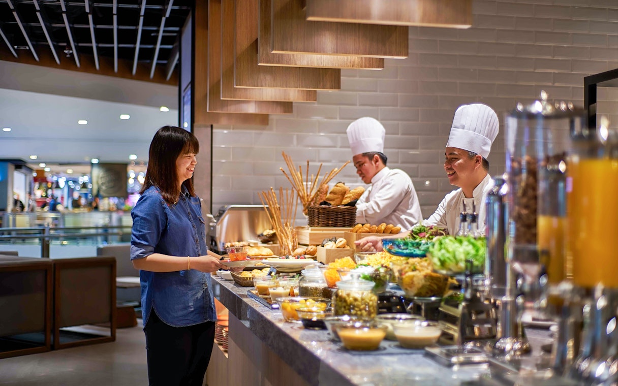 Guest enjoying buffet at Plaza Premium Lounge, KLIA Terminal 2, with chefs preparing food.
