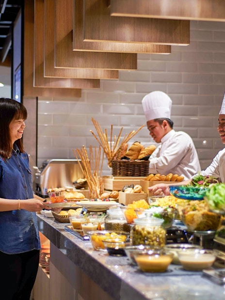 Guest enjoying buffet at Plaza Premium Lounge, KLIA Terminal 2, with chefs preparing food.