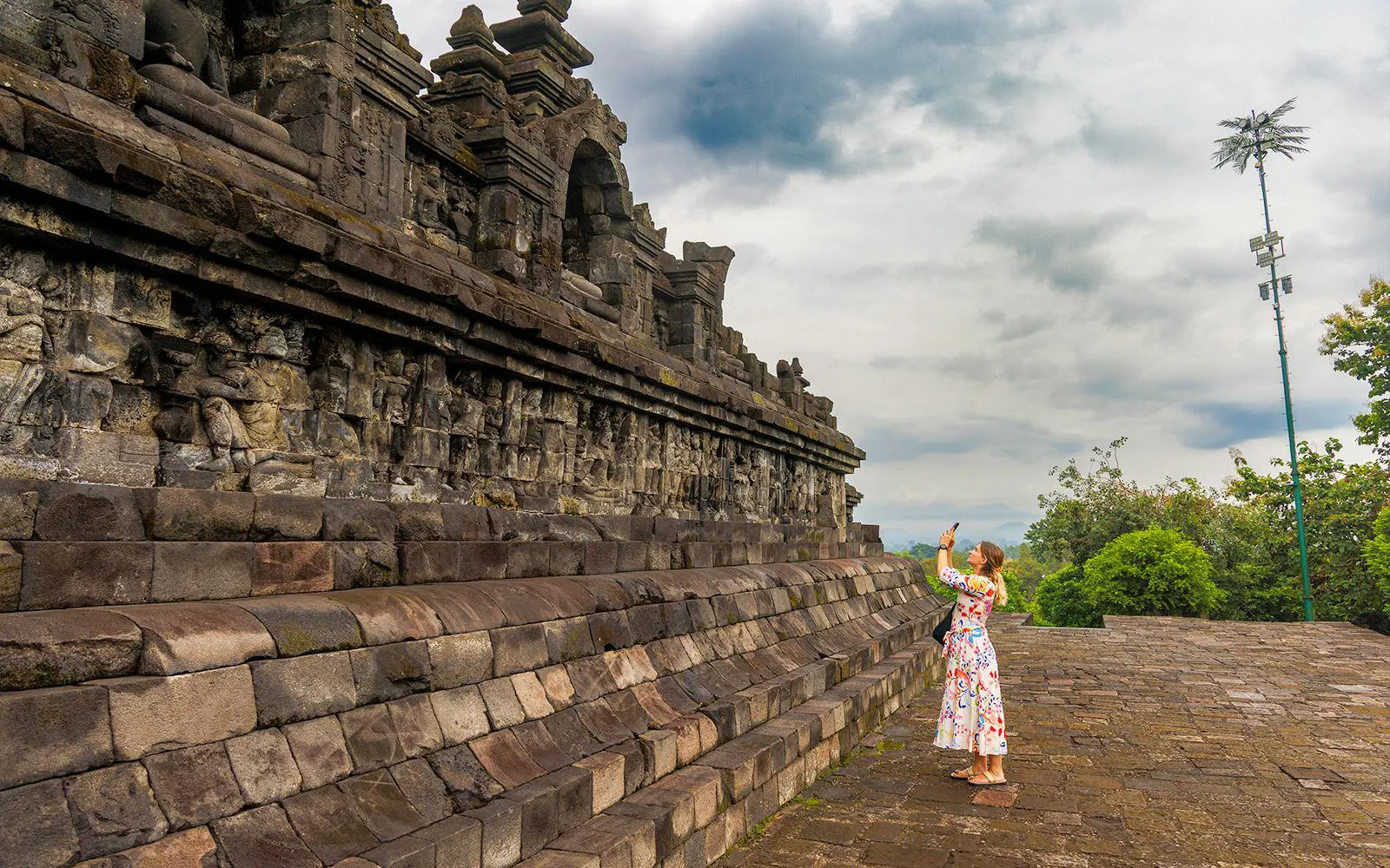 Woman photographing ancient stone carvings at Borobudur Temple, Indonesia.