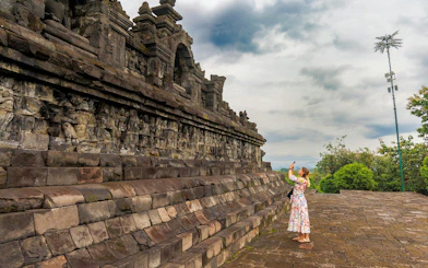 Woman photographing ancient stone carvings at Borobudur Temple, Indonesia.