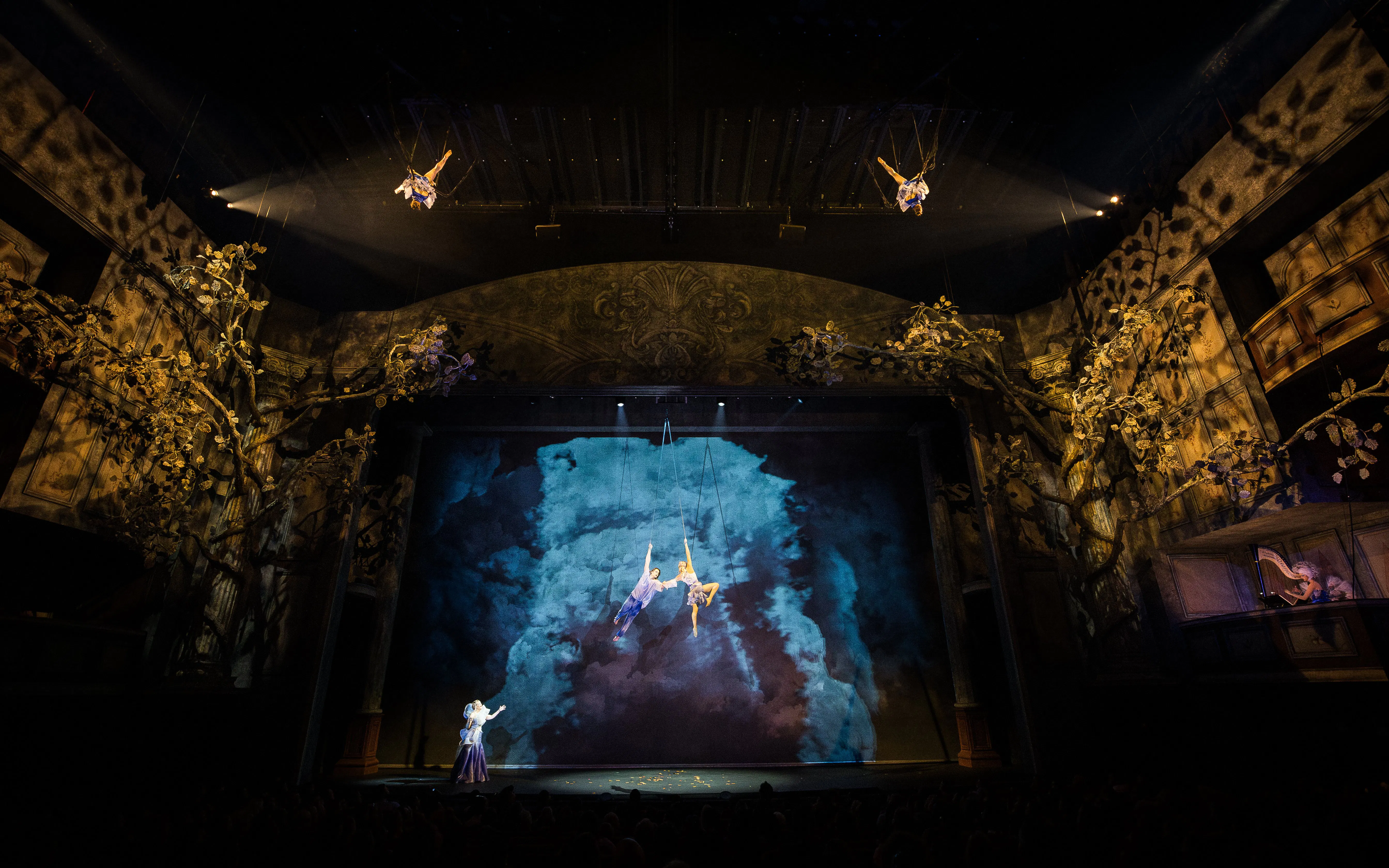 Cirque du Soleil Alizé performers suspended mid-air on a theatrical stage.
