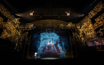 Cirque du Soleil Alizé performers suspended mid-air on a theatrical stage.