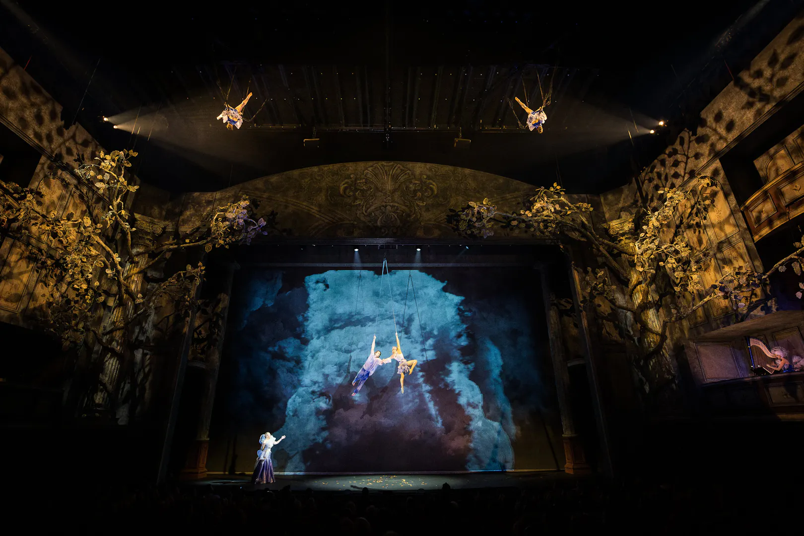 Cirque du Soleil Alizé performers suspended mid-air on a theatrical stage.