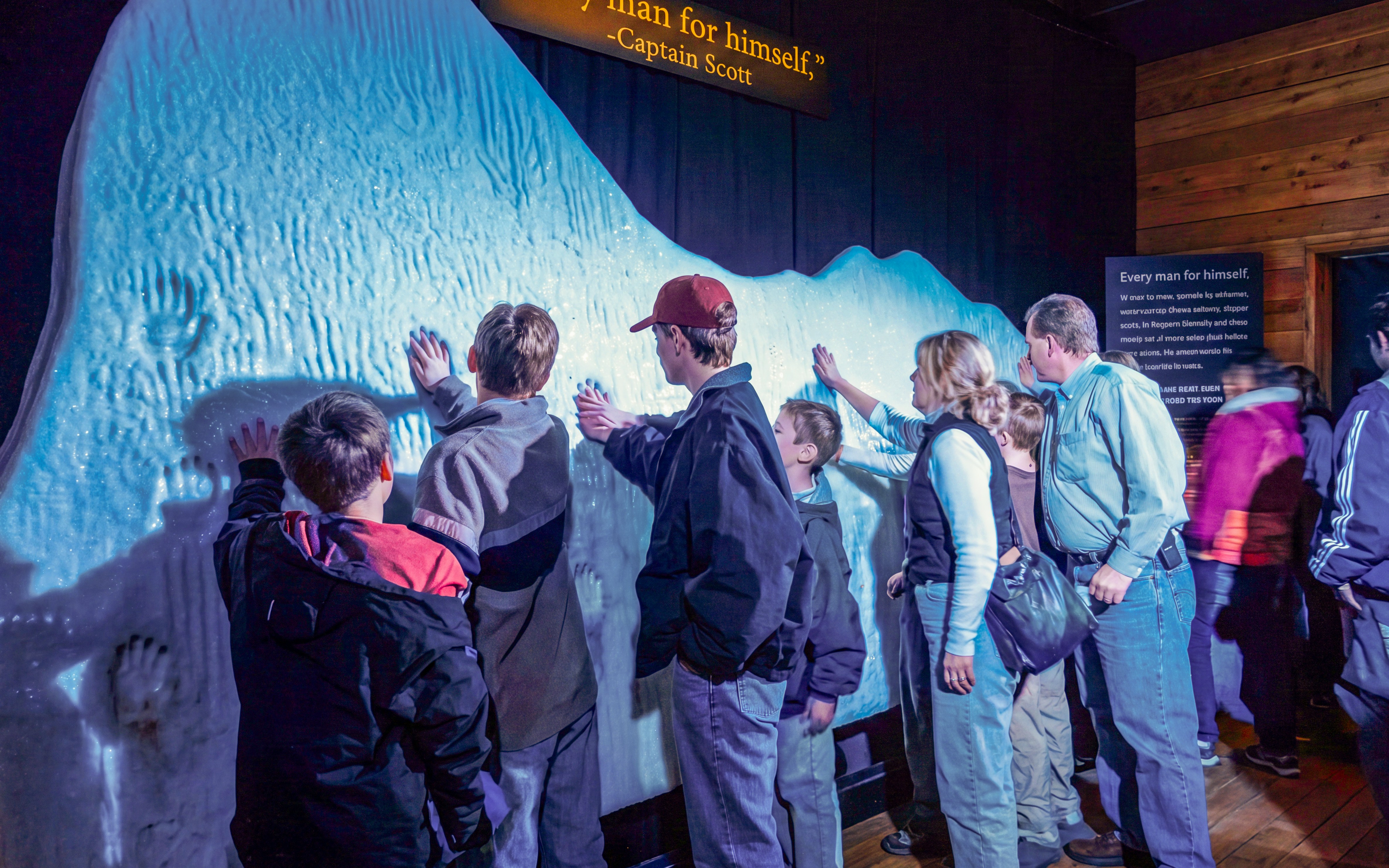 Visitors touching an iceberg replica at TITANIC: The Artifact Exhibition.