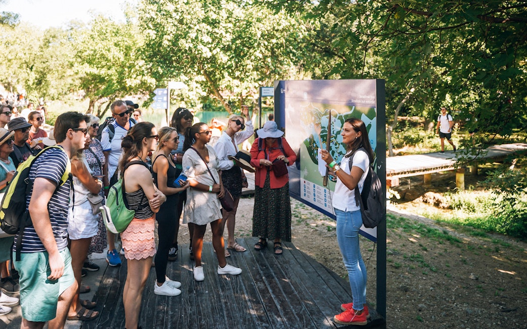 Tour group listening to a guide at Krka National Park during a Split wine tasting trip.