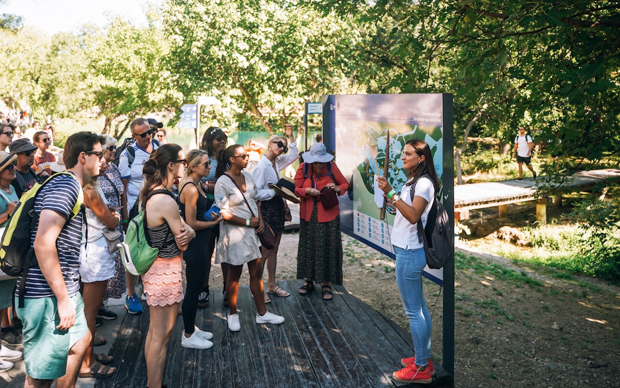 Tour group listening to a guide at Krka National Park during a Split wine tasting trip.