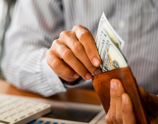 Hands placing money into a pocket, symbolizing financial transactions in a business context.
