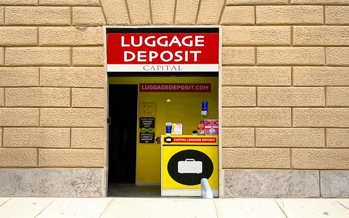 Luggage deposit service entrance in Rome with signage and operating hours.