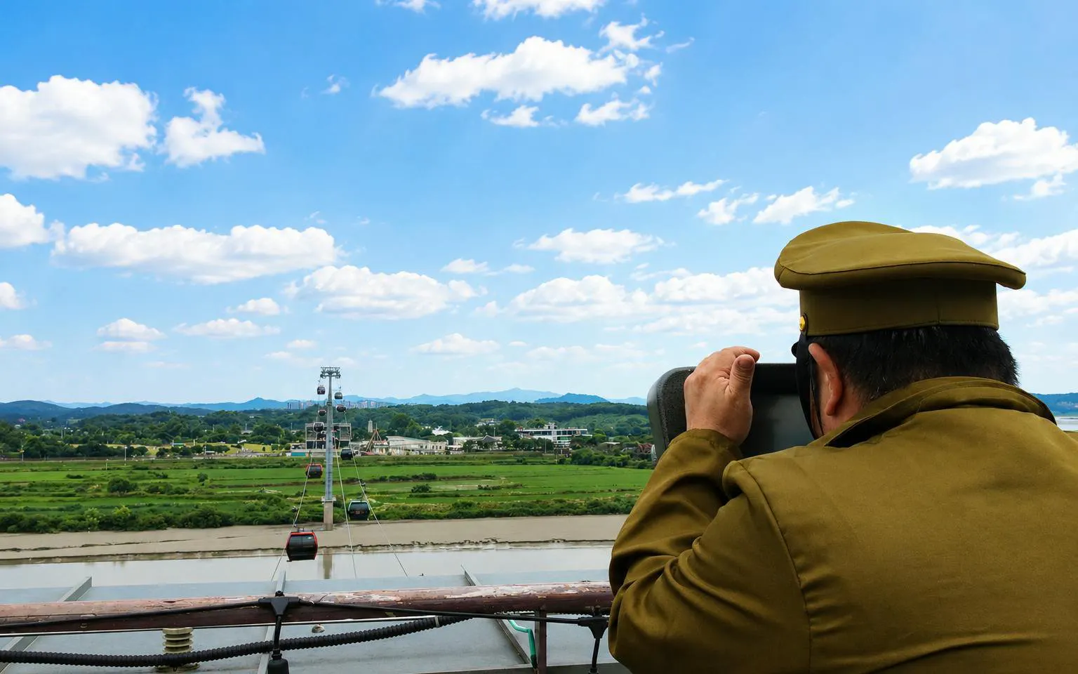 Person observing landscape from DMZ observatory during Half Day DMZ Tour with JSA Photo Zone.