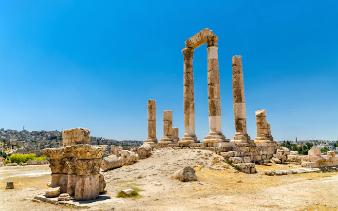 Temple of Hercules ruins at Amman Citadel, Jordan, with cityscape in the background.