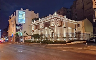 Historic building illuminated at night on a street in Bucharest, Romania.