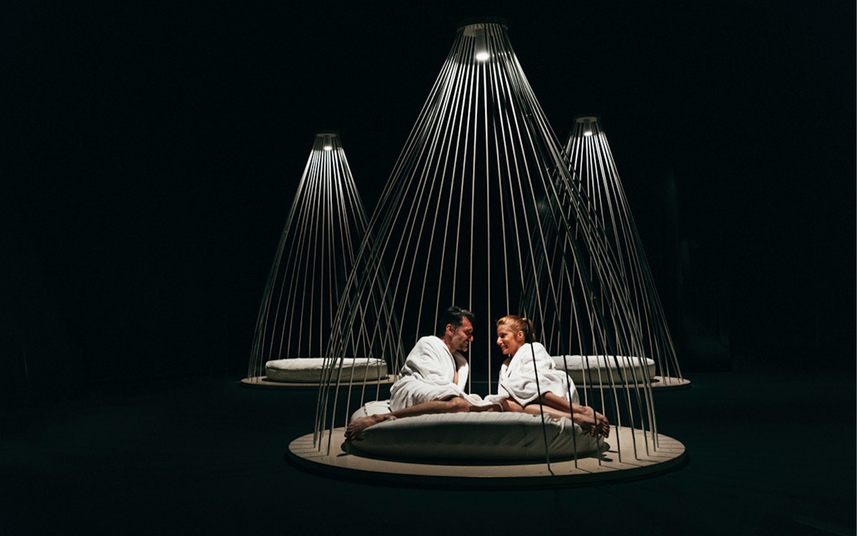 Couple relaxing in robes at QC Terme Milano Resort & Spa under modern lighting.