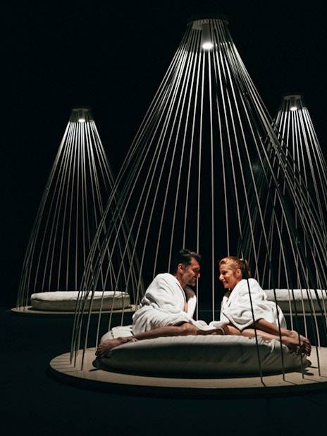 Couple relaxing in robes at QC Terme Milano Resort & Spa under modern lighting.