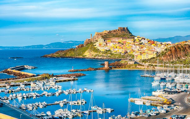 Harbor view of Castelsardo with colorful hillside buildings and medieval castle.