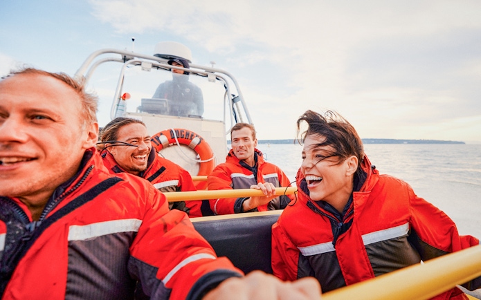 Four people in red jackets enjoying a Whale Watching Tour on a boat.