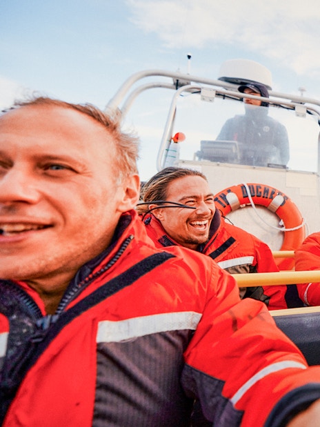Four people in red jackets enjoying a Whale Watching Tour on a boat.