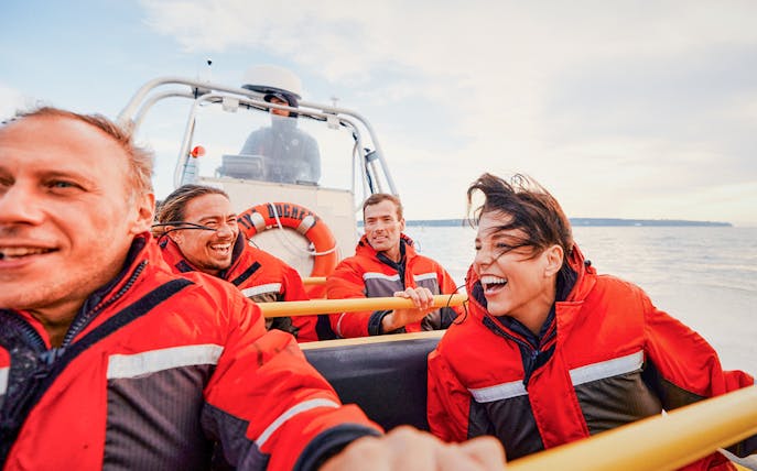 Four people on a Zodiac boat during a whale watching tour in Victoria, Canada.