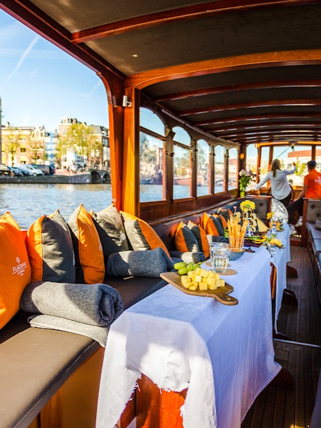 Luxury canal cruise in Amsterdam with cheese and wine setup on a boat.