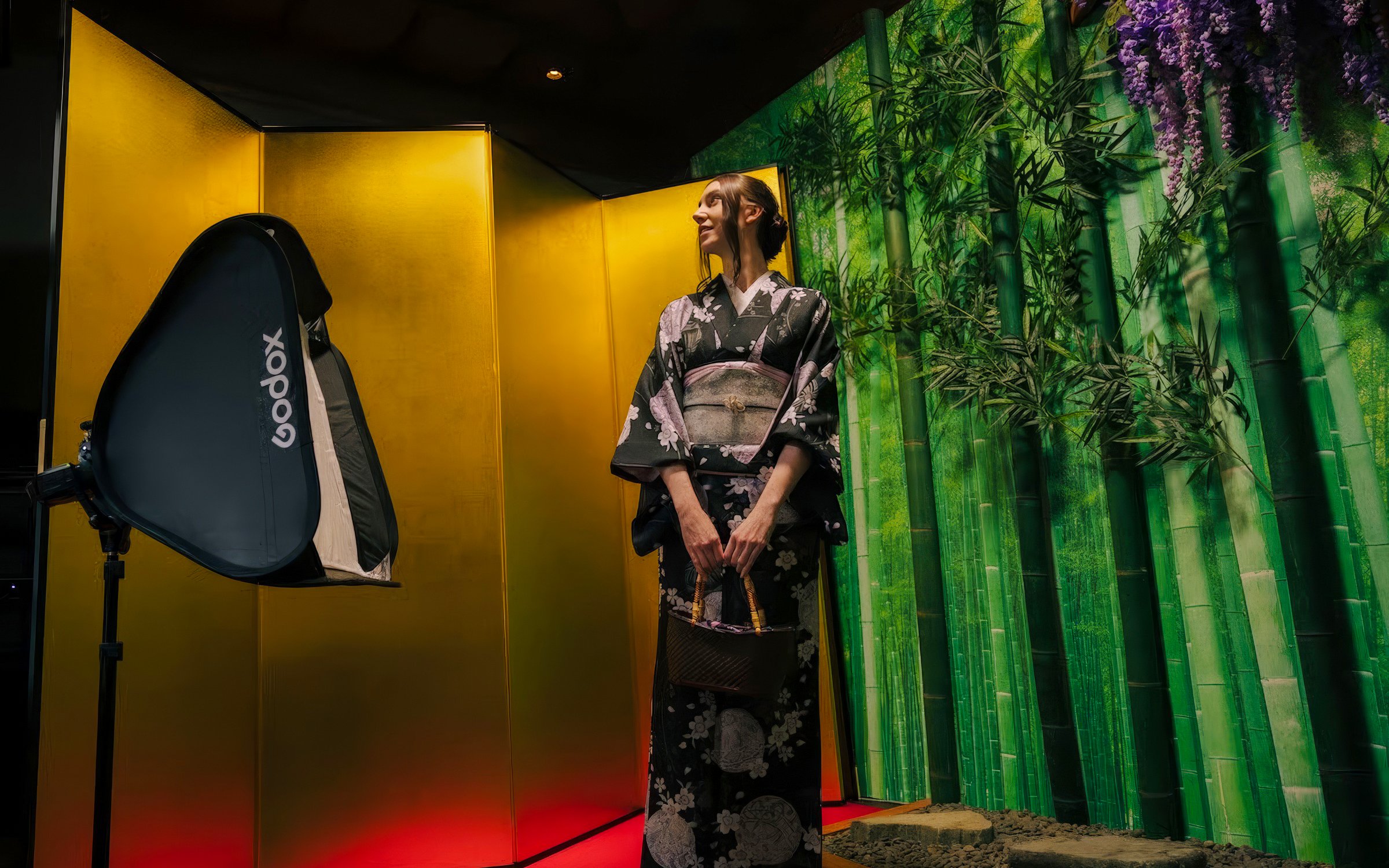 Tourist in kimono posing in front of bamboo-themed studio backdrop.