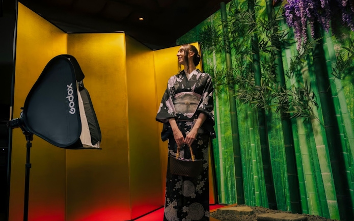 Tourist in kimono posing in front of bamboo-themed studio backdrop.