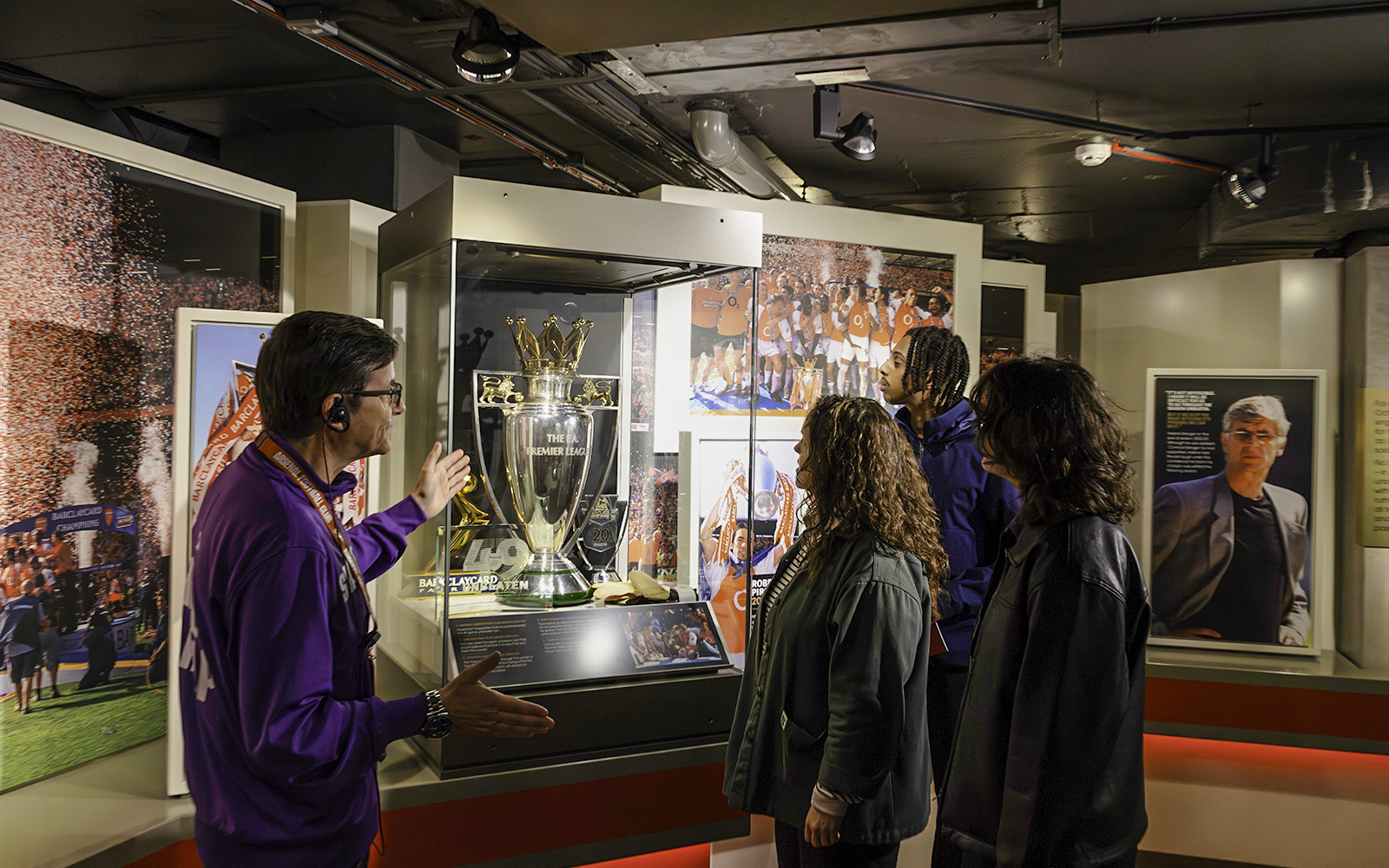 Visitors viewing Premier League trophy at Arsenal Museum, Emirates Stadium.