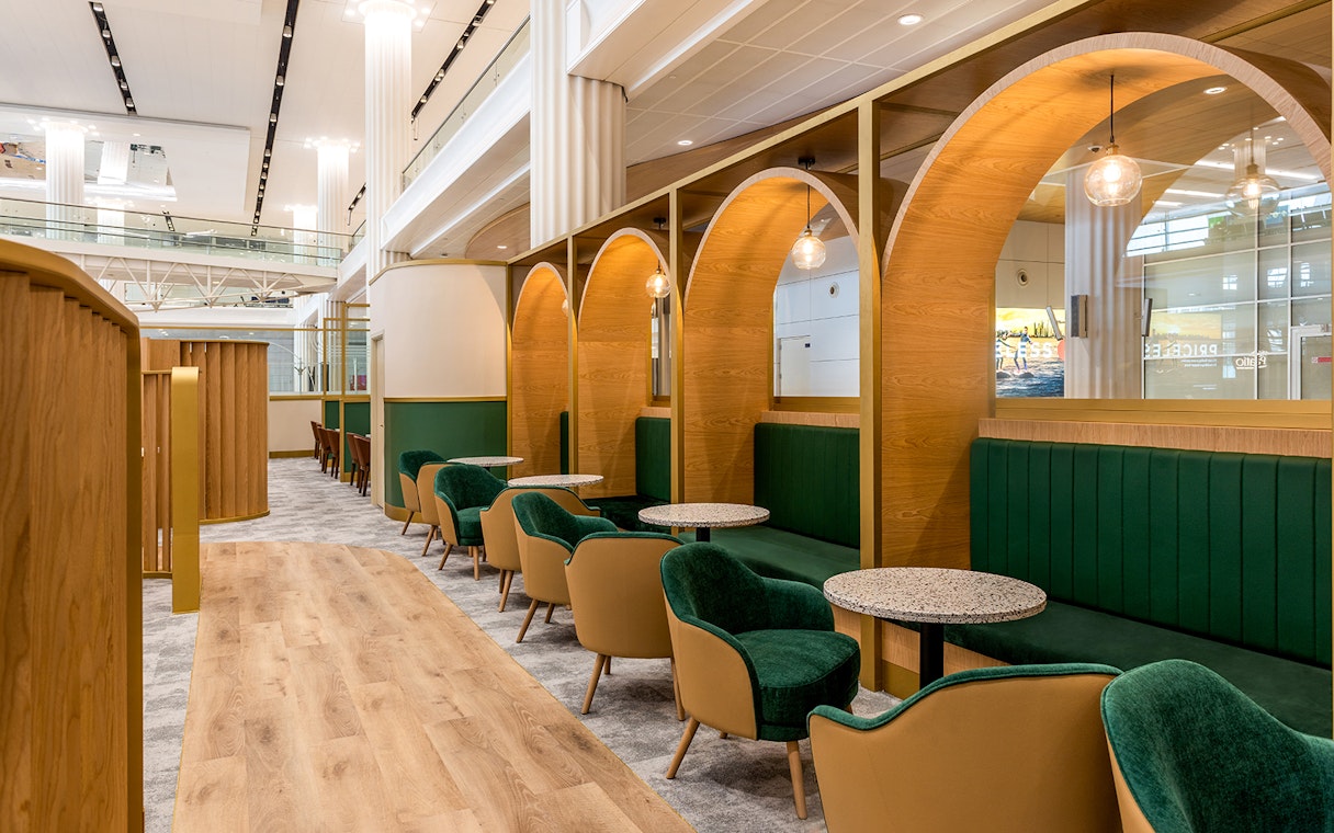 Premium lounge seating area at Dubai International Airport (DXB) with green chairs and wooden decor.
