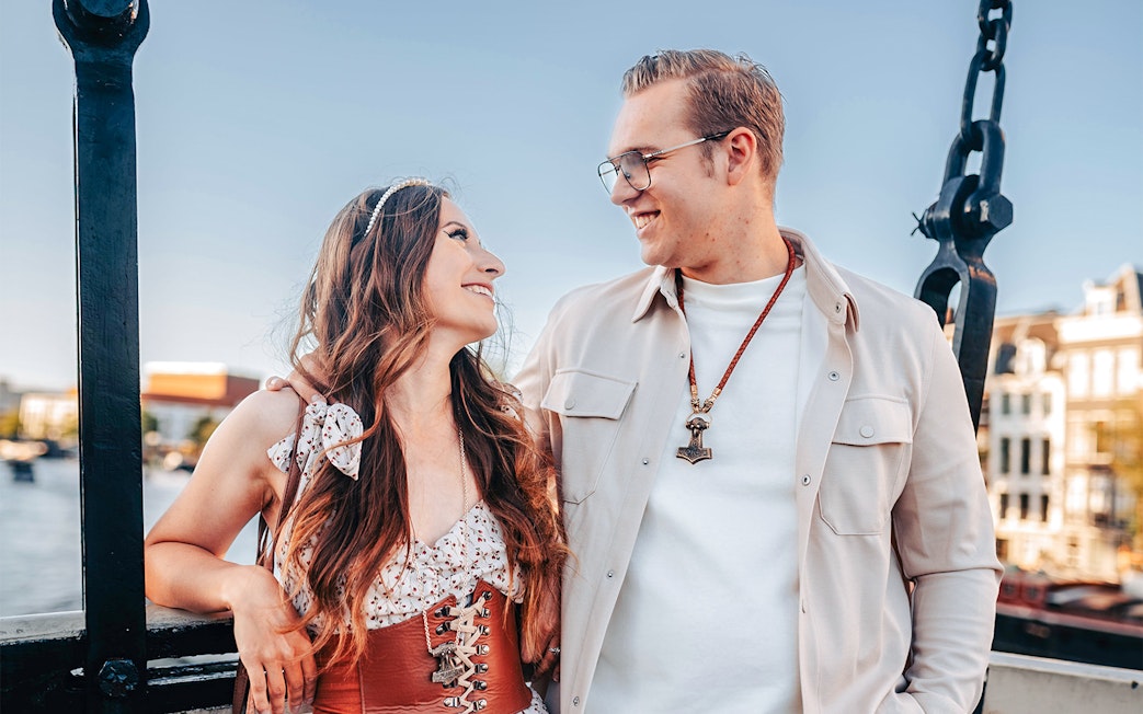 Couple smiling on Magere Brug during professional photoshoot in Amsterdam.