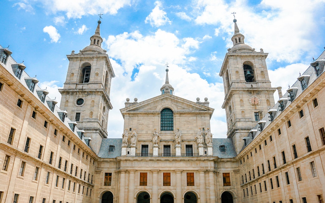 Royal Site of San Lorenzo de El Escorial facade with towers and statues, Spain.