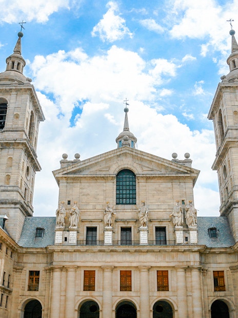 Royal Site of San Lorenzo de El Escorial facade with towers and statues, Spain.