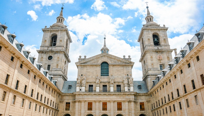 Royal Site of San Lorenzo de El Escorial facade with towers and statues, Spain.