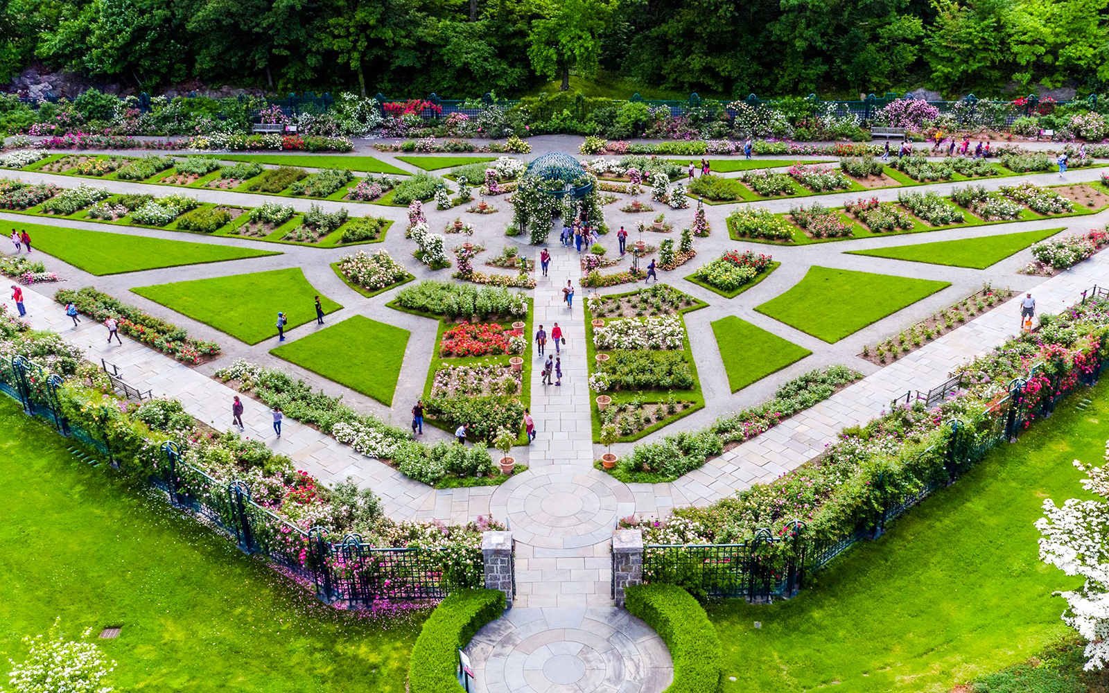 Visitors walking through pathways at New York Botanical Gardens, surrounded by vibrant flower beds.