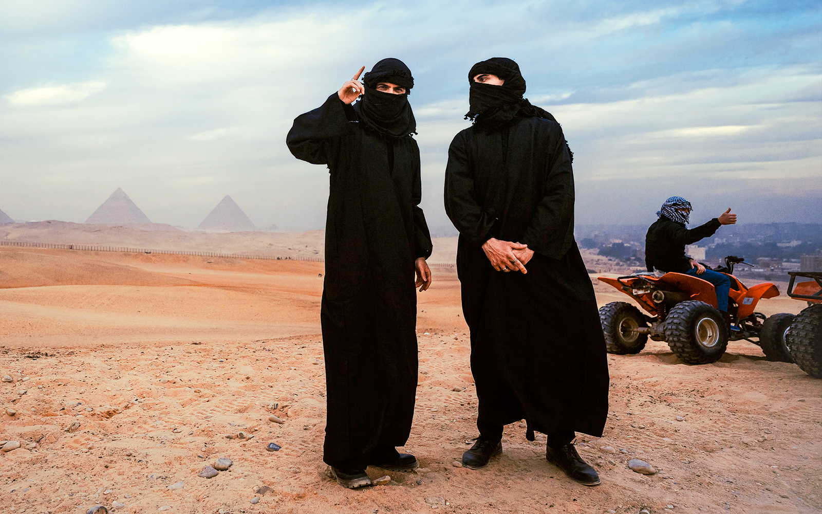 Tourists in traditional attire with ATVs near the Pyramids of Giza, Egypt.