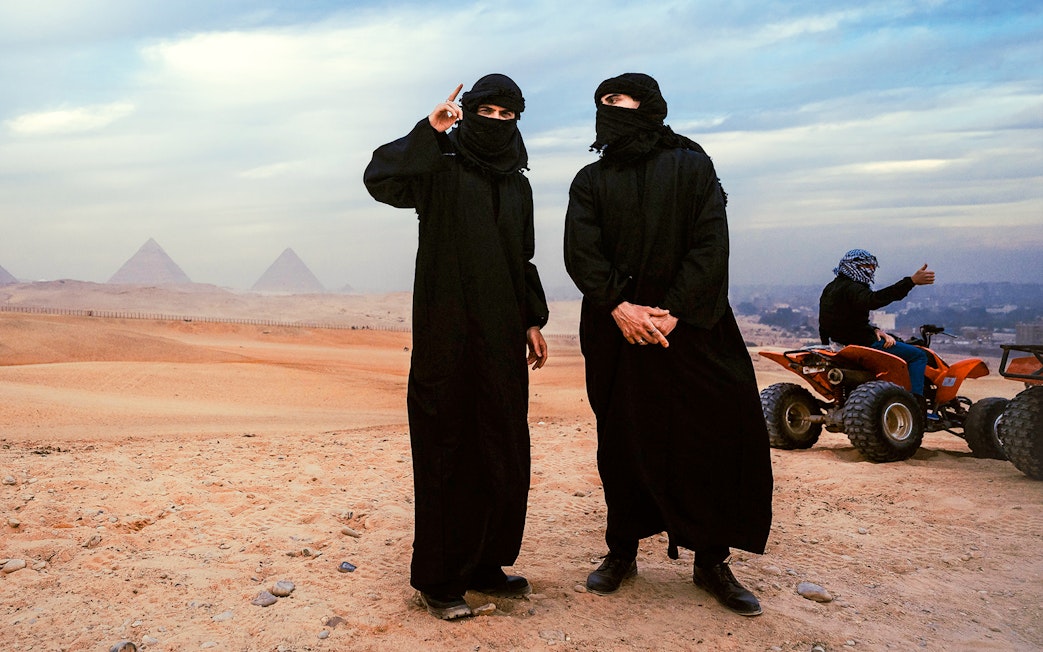 Tourists in traditional attire with ATVs near the Pyramids of Giza, Egypt.