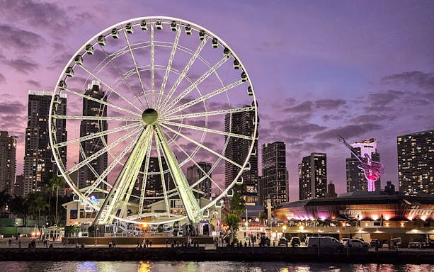 Miami skyline with Ferris wheel and cityscape at dusk, viewed from a luxury yacht cruise.